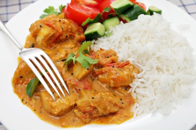 A Kerala or South Indian chicken curry, which includes tomatoes and coconut milk garnished with coreander and curry leaves and served with salad and rice